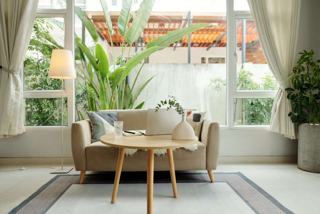 Designat vardagsrum med soffa och soffbord Stilrent vardagsrum med modern soffa, soffbord och gröna växter i naturligt ljus.